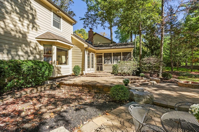 rear view of house featuring a patio area, a sunroom, and an outdoor fire pit