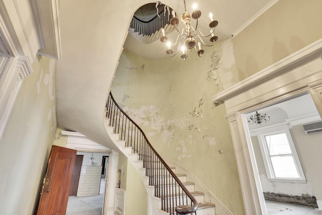 stairs with ornamental molding, a high ceiling, a wall mounted air conditioner, and a notable chandelier