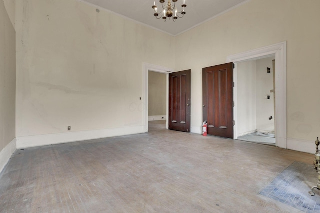 spare room with a high ceiling, crown molding, hardwood / wood-style floors, and a chandelier