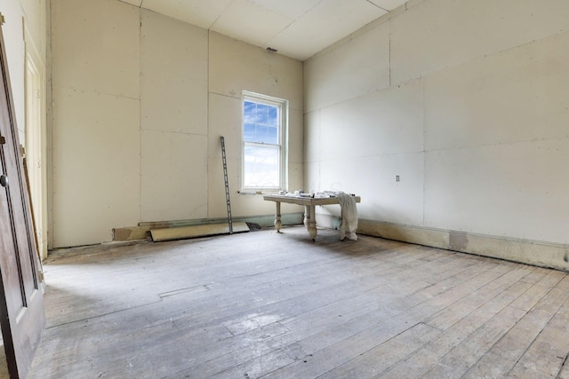 empty room with light hardwood / wood-style floors and a high ceiling