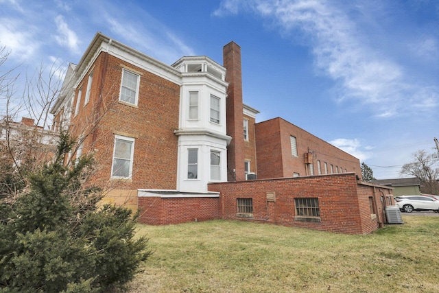 back of property with a yard and central AC