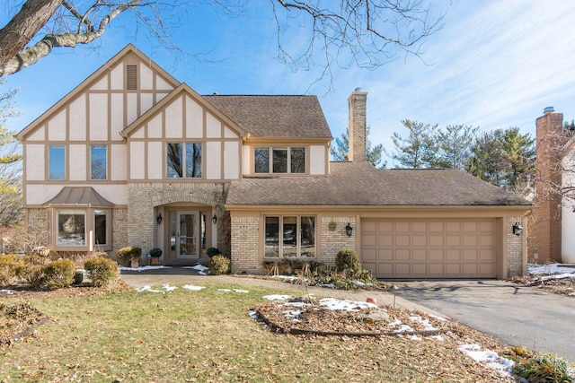 tudor-style house featuring a garage and a front yard