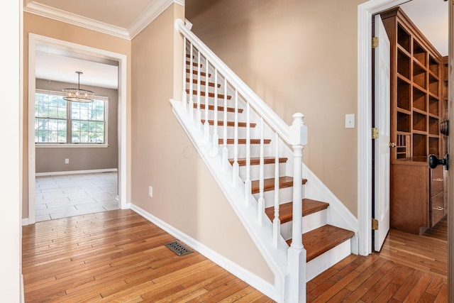 stairs with hardwood / wood-style floors and crown molding