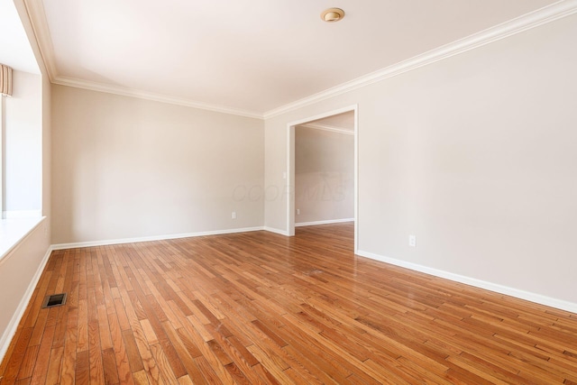 empty room with ornamental molding and light wood-type flooring