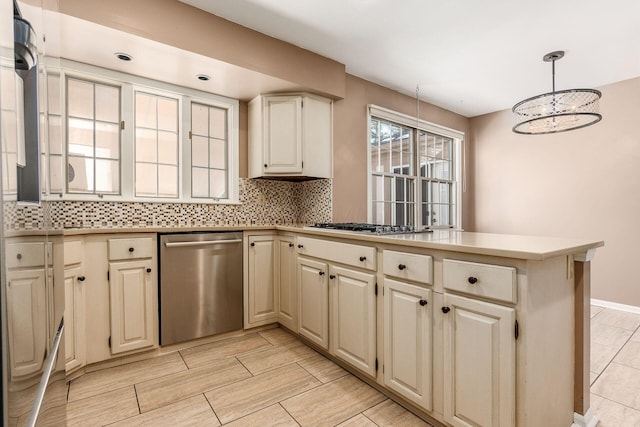 kitchen with tasteful backsplash, hanging light fixtures, a notable chandelier, kitchen peninsula, and stainless steel appliances