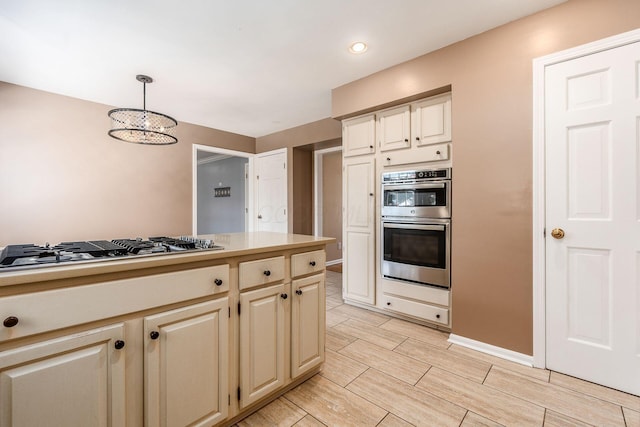 kitchen featuring pendant lighting, a notable chandelier, stainless steel appliances, and cream cabinetry