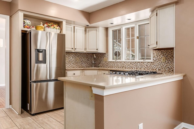 kitchen featuring stainless steel appliances, decorative backsplash, white cabinets, and kitchen peninsula