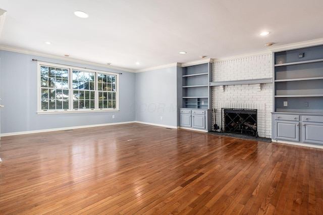 unfurnished living room featuring a brick fireplace, hardwood / wood-style flooring, ornamental molding, and built in shelves