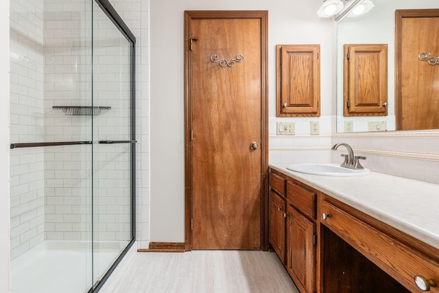 bathroom with vanity, backsplash, a shower with shower door, and wood-type flooring