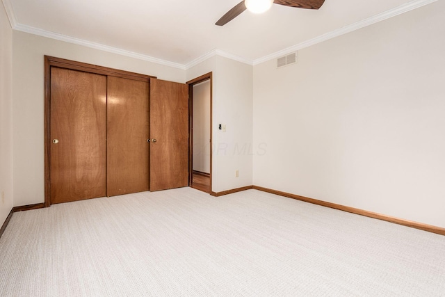 unfurnished bedroom with ornamental molding, light colored carpet, a closet, and ceiling fan