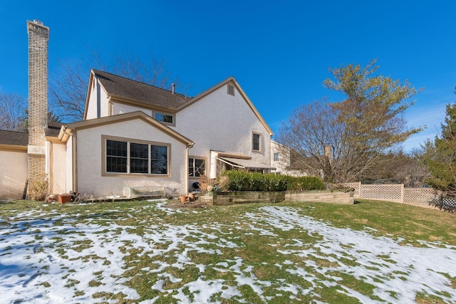 snow covered rear of property with a yard