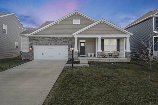 craftsman-style house featuring a garage, covered porch, and a lawn