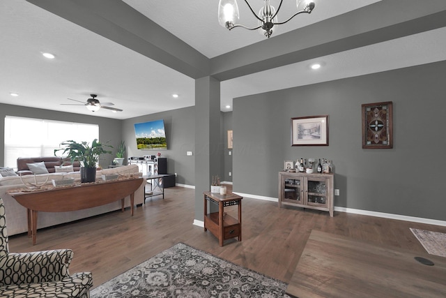 living room featuring ceiling fan with notable chandelier and dark wood-type flooring