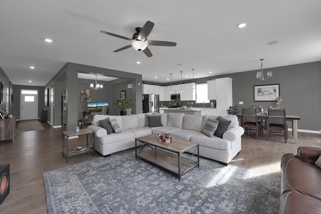 living room with dark hardwood / wood-style flooring and ceiling fan with notable chandelier