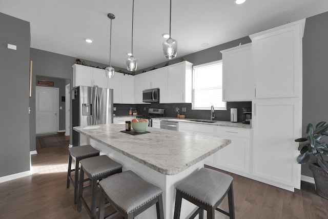 kitchen featuring sink, white cabinetry, decorative light fixtures, a kitchen island, and stainless steel appliances