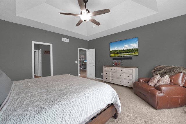 bedroom with light carpet, a raised ceiling, and ceiling fan