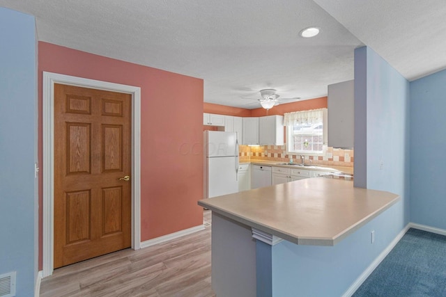 kitchen with a breakfast bar, tasteful backsplash, kitchen peninsula, white appliances, and white cabinets