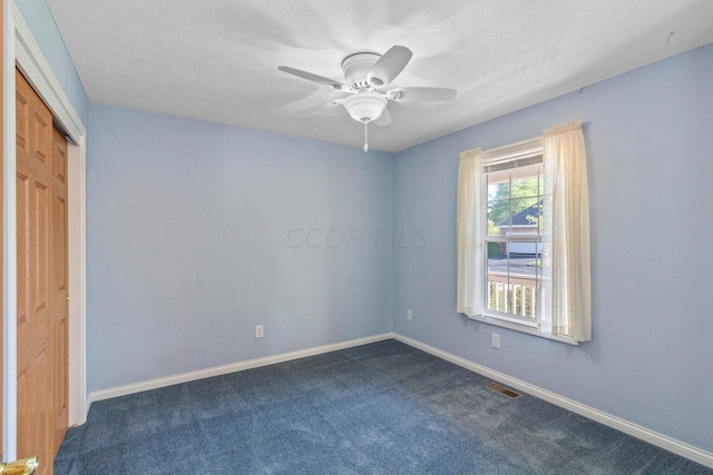 carpeted spare room with a textured ceiling and ceiling fan