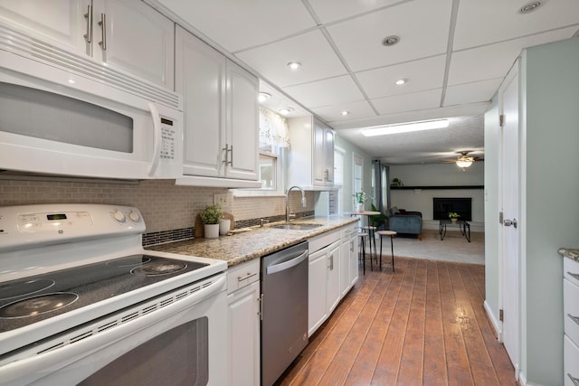 kitchen featuring dark wood-type flooring, sink, white cabinetry, tasteful backsplash, and white appliances