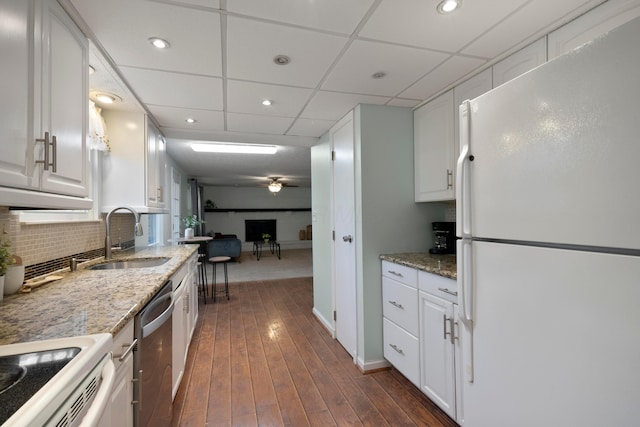 kitchen featuring sink, white appliances, backsplash, light stone counters, and white cabinets