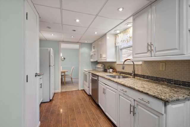 kitchen with sink, white appliances, white cabinetry, tasteful backsplash, and light stone counters