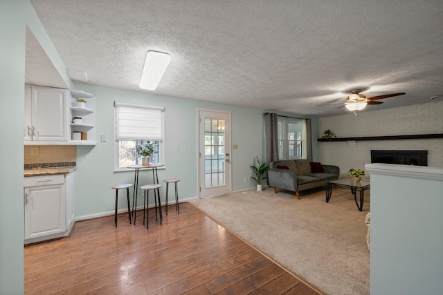 living room featuring hardwood / wood-style flooring, ceiling fan, a textured ceiling, and a fireplace