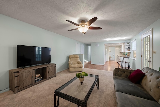 carpeted living room featuring ceiling fan and a textured ceiling