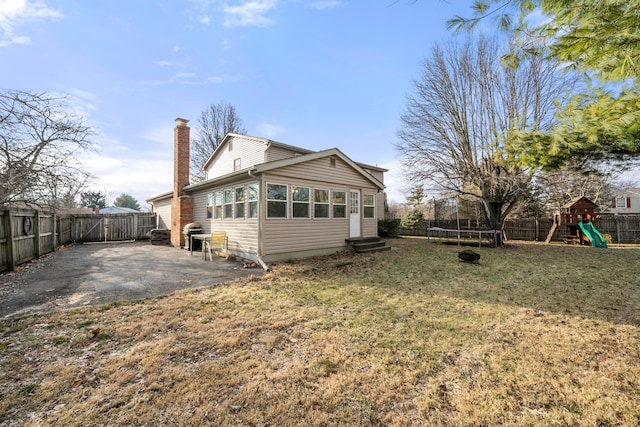 back of house featuring a playground, a lawn, a trampoline, and a patio area