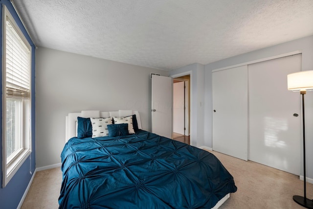 carpeted bedroom with a textured ceiling and a closet