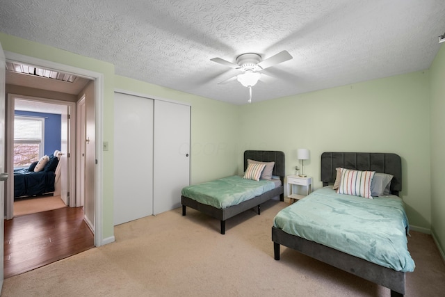 carpeted bedroom featuring a textured ceiling, a closet, and ceiling fan