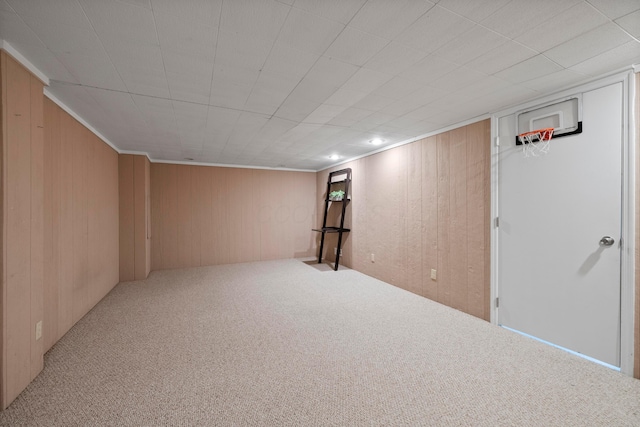 basement featuring light colored carpet and wooden walls