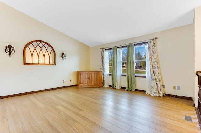 spare room featuring vaulted ceiling and light hardwood / wood-style flooring