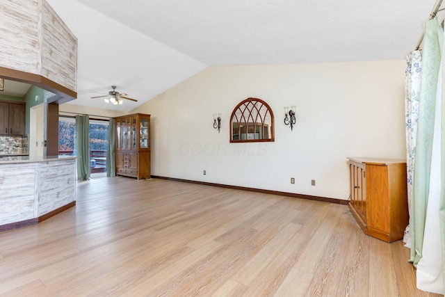 unfurnished living room featuring ceiling fan, vaulted ceiling, and light wood-type flooring