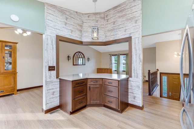 kitchen with a towering ceiling, a notable chandelier, stainless steel refrigerator, and light wood-type flooring