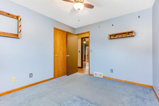 spare room featuring ceiling fan, carpet flooring, and a textured ceiling