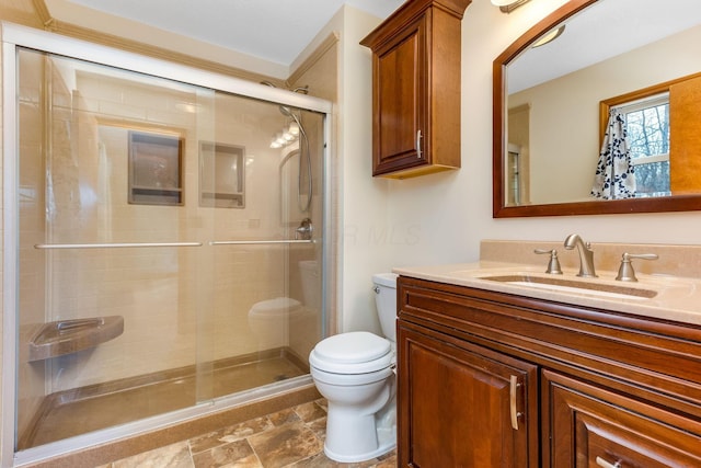 bathroom featuring vanity, a shower with door, and toilet