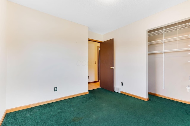 unfurnished bedroom with dark carpet and a closet