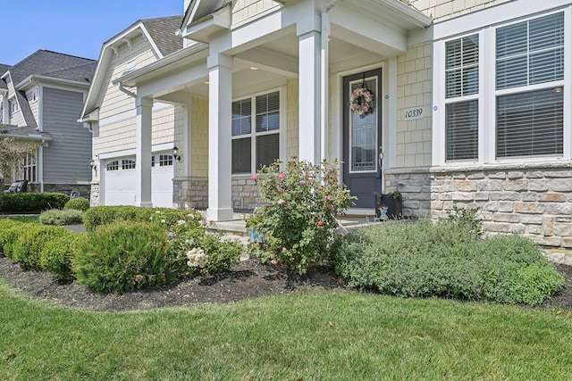 view of exterior entry with covered porch and a lawn