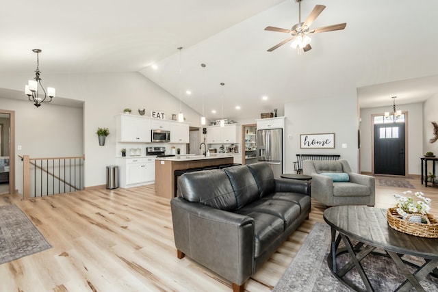 living room with high vaulted ceiling, sink, ceiling fan with notable chandelier, and light hardwood / wood-style floors