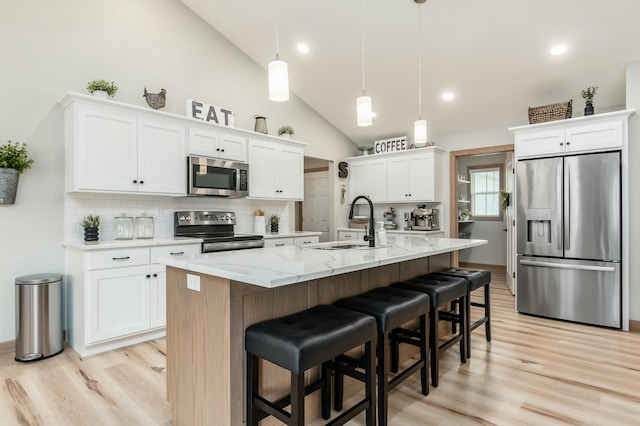 kitchen featuring stainless steel appliances, pendant lighting, a center island with sink, and white cabinets