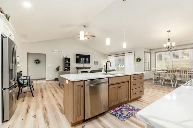 kitchen featuring sink, decorative light fixtures, light wood-type flooring, stainless steel appliances, and a kitchen island with sink