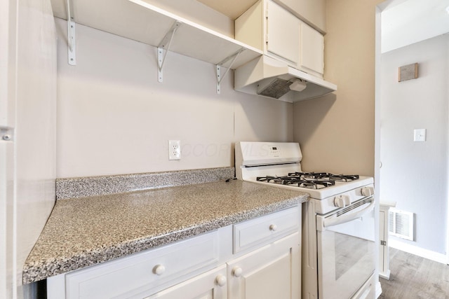 kitchen featuring white cabinetry, light stone counters, white gas range oven, and hardwood / wood-style floors