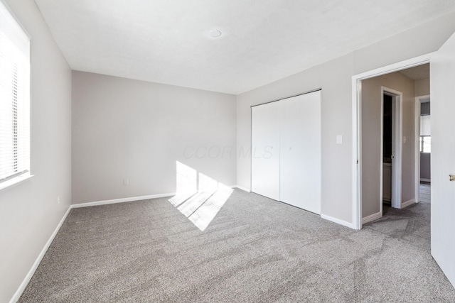 unfurnished bedroom with light colored carpet and a closet