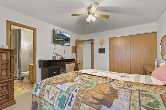 bedroom with ensuite bath, light carpet, a textured ceiling, a closet, and ceiling fan