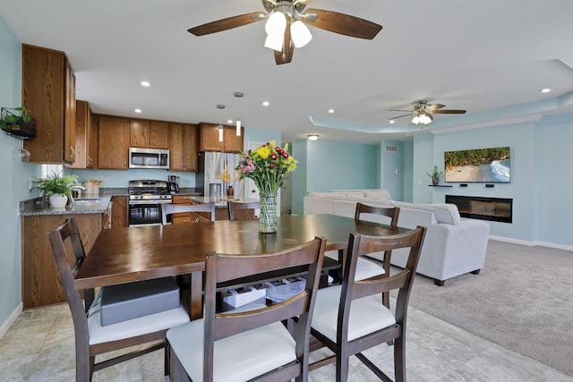 carpeted dining area with a raised ceiling and sink