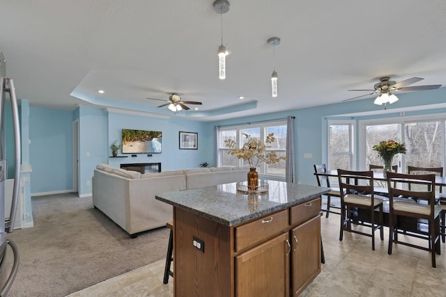 kitchen with a healthy amount of sunlight, a tray ceiling, decorative light fixtures, and a kitchen island