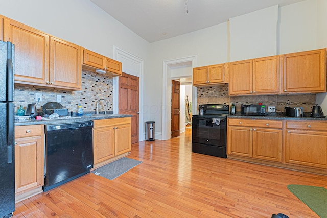 kitchen featuring sink, light wood-type flooring, decorative backsplash, and black appliances