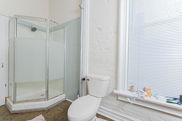 bathroom featuring a shower with door and toilet