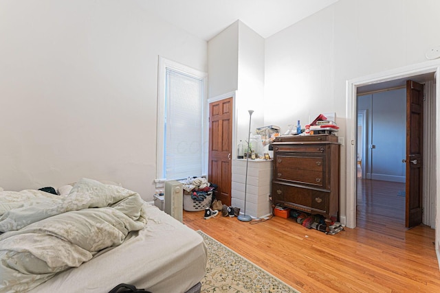 bedroom with a towering ceiling and light hardwood / wood-style floors