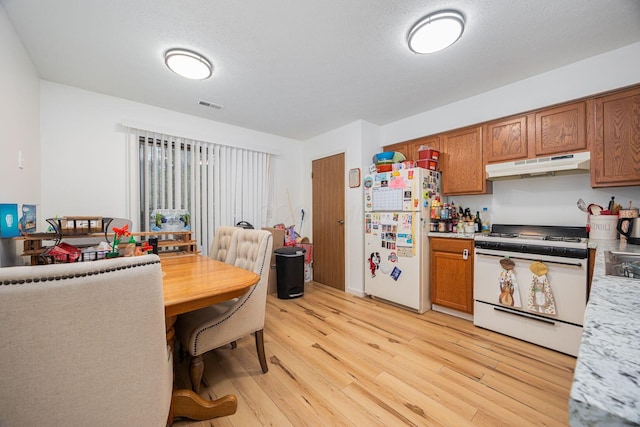 kitchen with white appliances, light hardwood / wood-style floors, and a textured ceiling